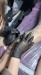 Tattoo artist applies bat design to client's calf