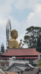 Golden Buddha statue observed among red-roofed buildings in Đà Lạt