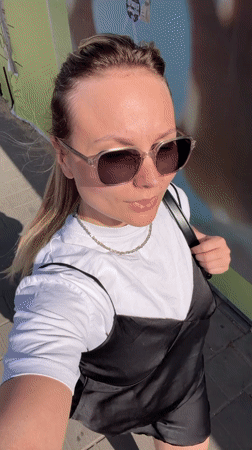 Woman films selfie video on sunny Bat Yam sidewalk