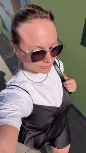 Woman films selfie video on sunny Bat Yam sidewalk