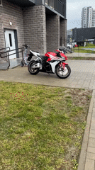 Honda CBR and electric scooter parked by brick building