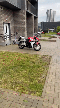 Honda CBR and electric scooter parked by brick building
