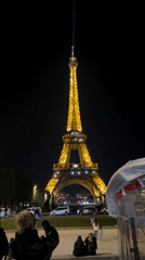 Eiffel Tower glows yellow as tourists gather for photos