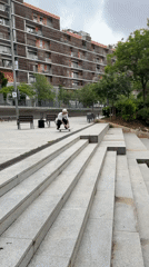 Skateboarder performs tricks in Barcelona area plaza, spring blooms observed