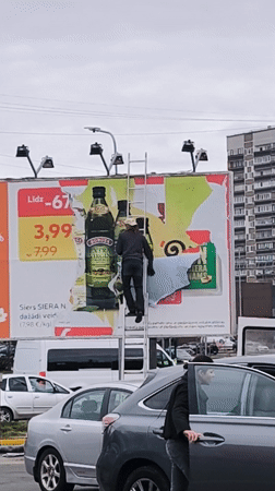 Billboard maintenance worker updates advertisements in Riga