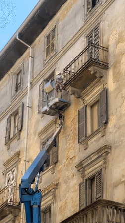 Construction worker performs building maintenance from hydraulic lift in Milano