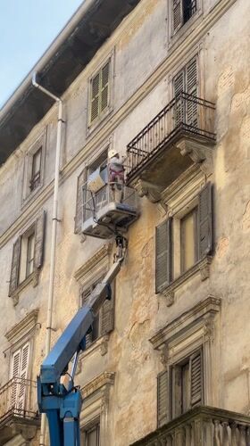 Construction worker performs building maintenance from hydraulic lift in Milano