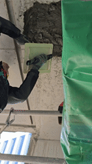Construction worker repairs ceiling with stucco over wire mesh