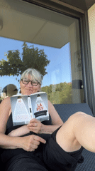 Woman gives thumbs up while reading on French patio
