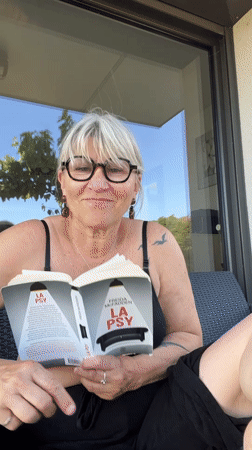 Woman gives thumbs up while reading on French patio