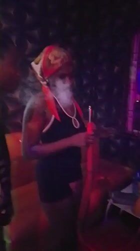 Woman with hookah captured in colorful lighting in Yelwa