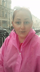 Woman films in pink raincoat during wet weather in Saint Petersburg
