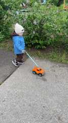 Toddler plays with toy truck on sidewalk in Russia