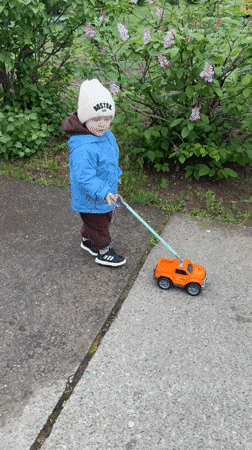 Toddler plays with toy truck on sidewalk in Russia