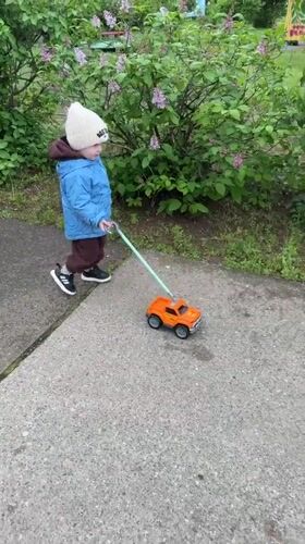 Toddler plays with toy truck on sidewalk in Russia