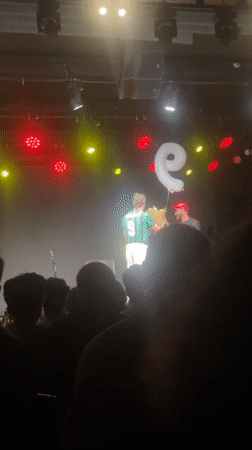 Soccer-jersey clad performer holds letter balloon on Tel Aviv stage