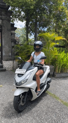 Woman with phone observed on parked scooter in Kuta