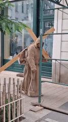 Robed figure carries wooden cross through Vienna city center