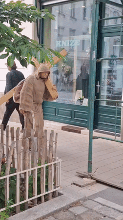 Robed figure carries wooden cross through Vienna city center