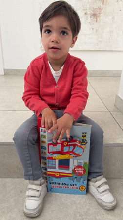 Toddler reads firefighter sound book in Luxembourg home Friday morning