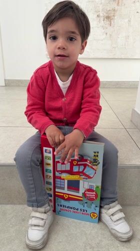 Toddler reads firefighter sound book in Luxembourg home Friday morning