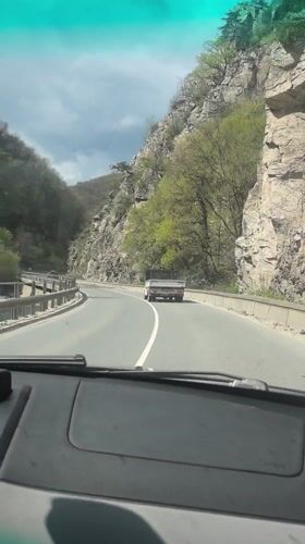 Driver navigates mountain road in Bulgaria under overcast skies