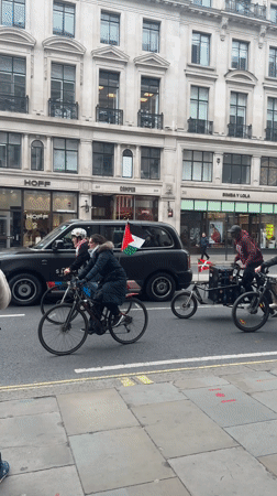Cyclists carry Palestinian flags through central London streets