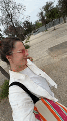 Woman with striped bag walks through Glifada, Greece