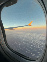 Passenger captures sunrise view from airplane window over clouds