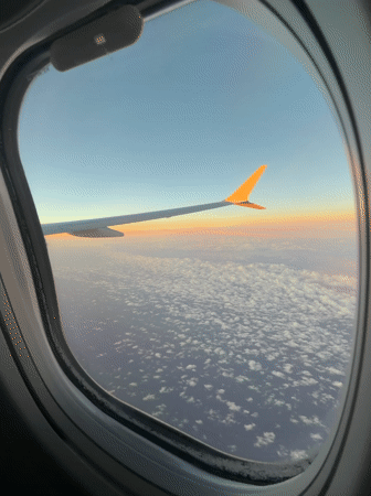 Passenger captures sunrise view from airplane window over clouds