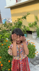 Child plays in rooftop garden among marigolds in Dhaka