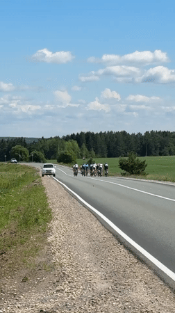 Cycling group rides rural road near Niva, Russia