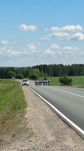 Cycling group rides rural road near Niva, Russia