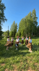 Women dance in coordinated outfits in sunny Russian field