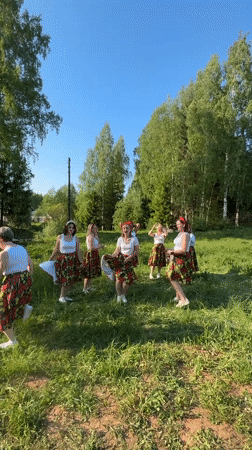 Women dance in coordinated outfits in sunny Russian field