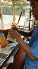 South Jakarta street vendor packs sauced snacks at a busy food cart