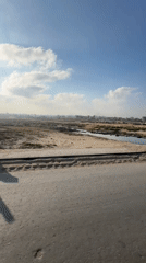 Dry borderland landscape with scattered people and makeshift structures