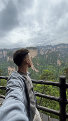Tourist photographs scenic mountain views from wooden platform in Luoguta