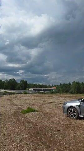A truck drives across a bridge under a cloudy sky.