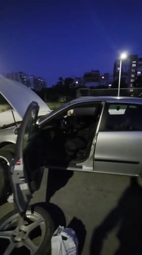 Silver sedan with hood open on a Varna street at dusk