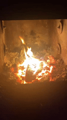 Wood burns in fireplace enclosure in Russian village
