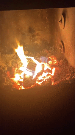Wood burns in fireplace enclosure in Russian village