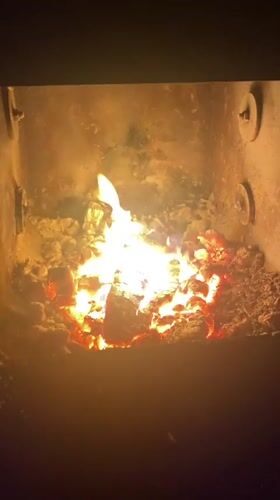 Wood burns in fireplace enclosure in Russian village