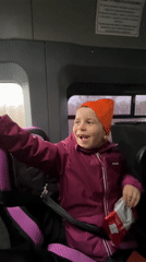 Child in car seat waves while traveling in Niva