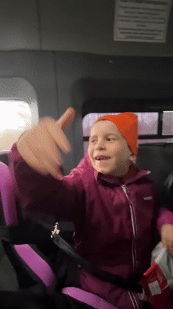 Child in car seat waves while traveling in Niva