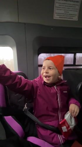 Child in car seat waves while traveling in Niva