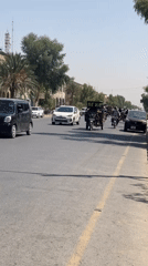 Heavily loaded motorcycle navigates busy Kandahar street traffic