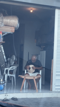 Man crafting woven object in Kutuh building