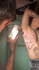 Man photographs tattooed torso with phone light in Buenos Aires