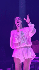 Woman performs on stage in purple lighting, Thailand